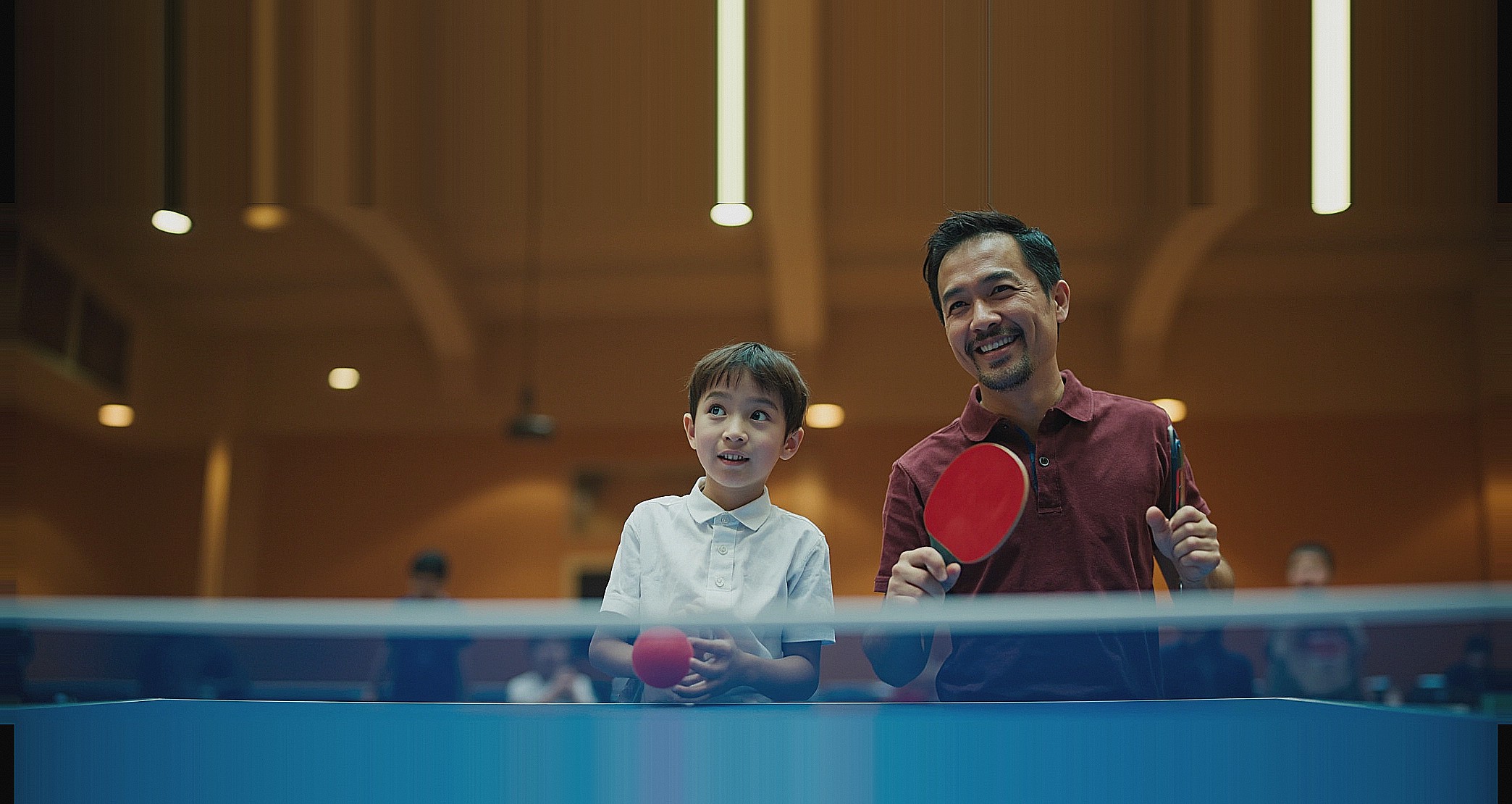 Coach and junior student facing the camera at a table tennis training table
